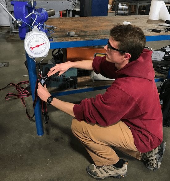 Enoch tests the strength of our PLA brackets, using a welded fixture to mimic the actuator, ratchet straps to apply force, and a spring scale to measure.