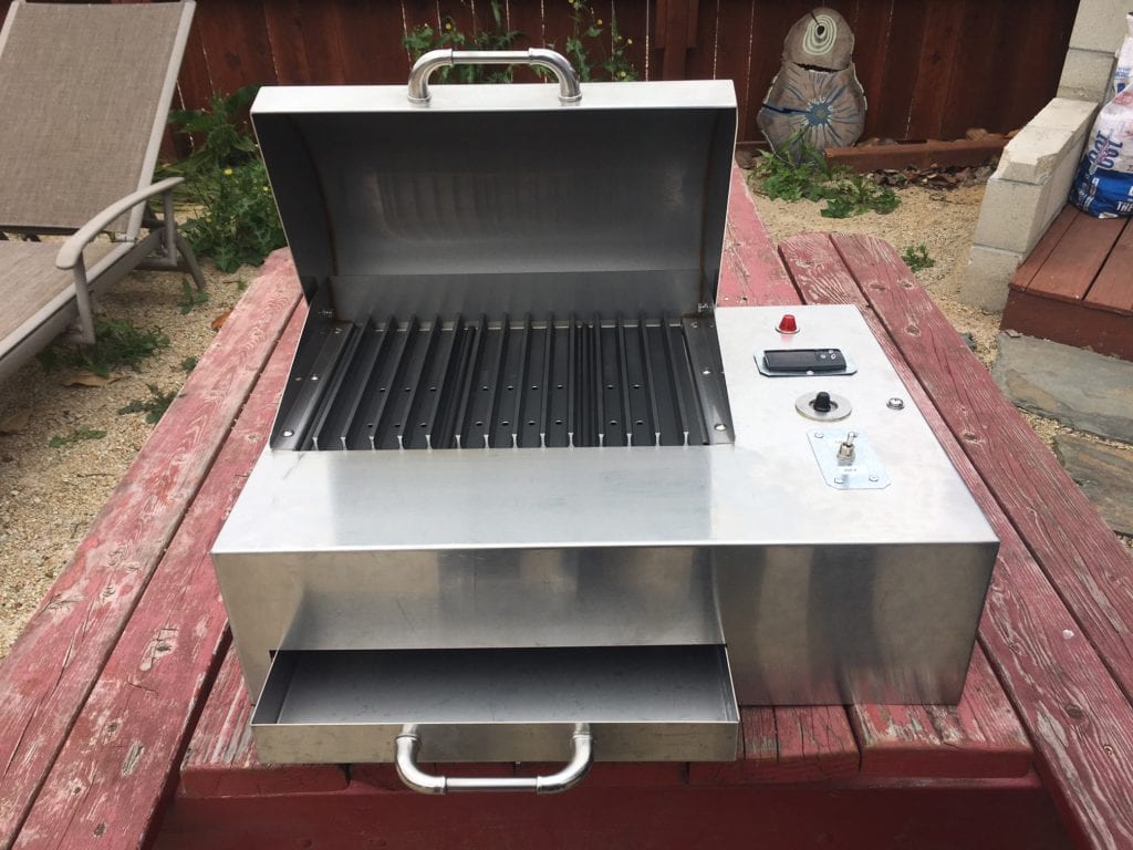 Front view of grill with lid open and drawer open