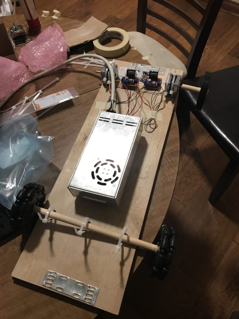 Grainy image of plywood with motors attached and a large battery in the center.